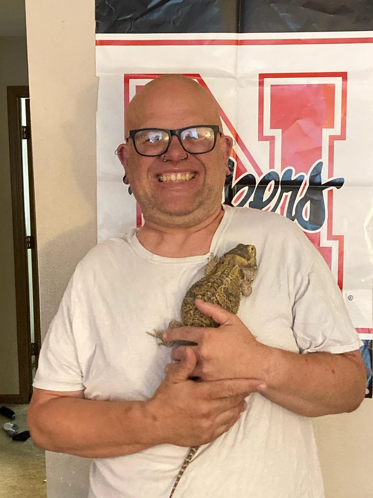 Brian E., a client at AmeriServe, smiling and holding his pet bearded dragon, showcasing his love for animals and the support he receives.