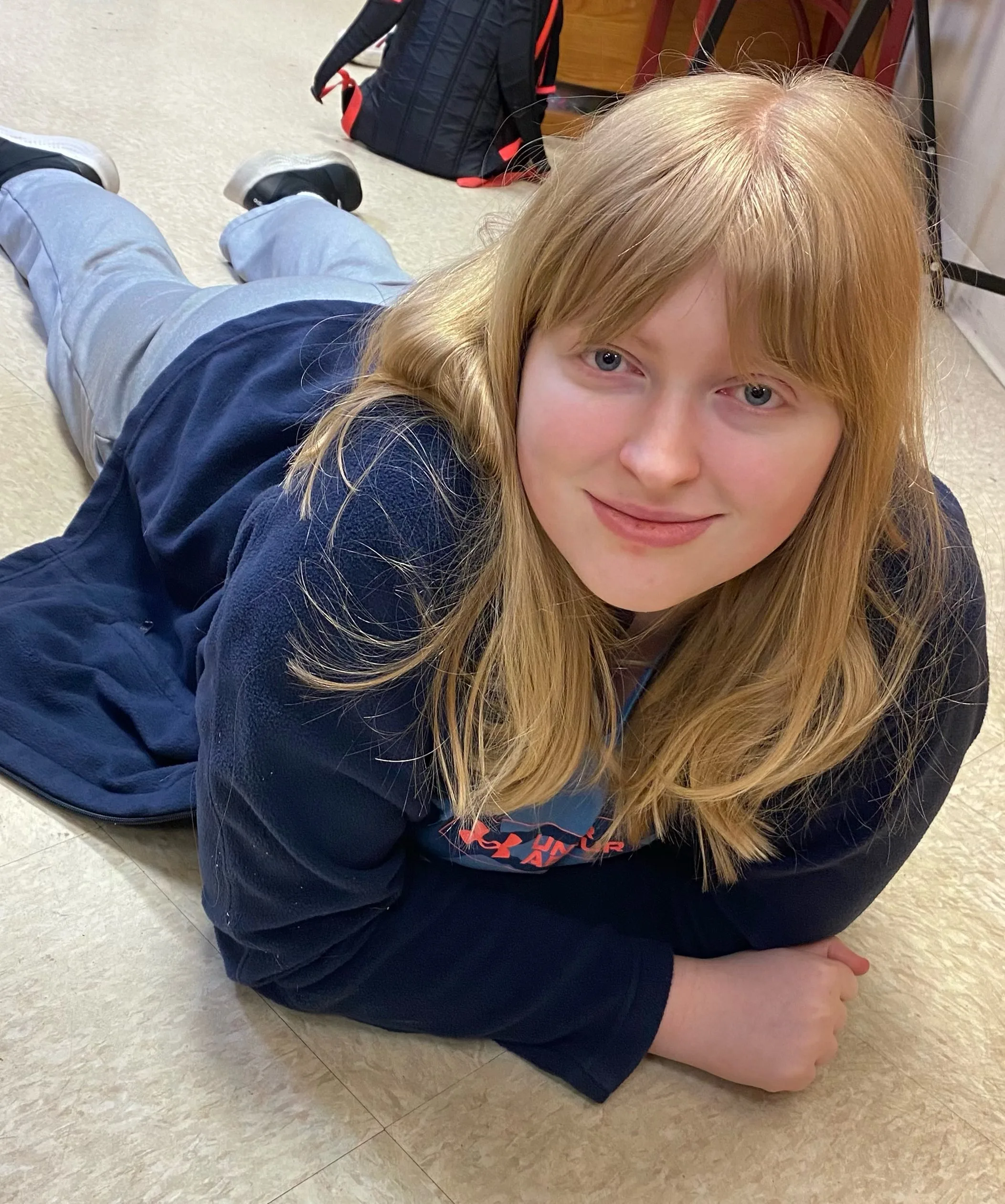 Maysen smiling and laying on the floor at AmeriServe DayHab.