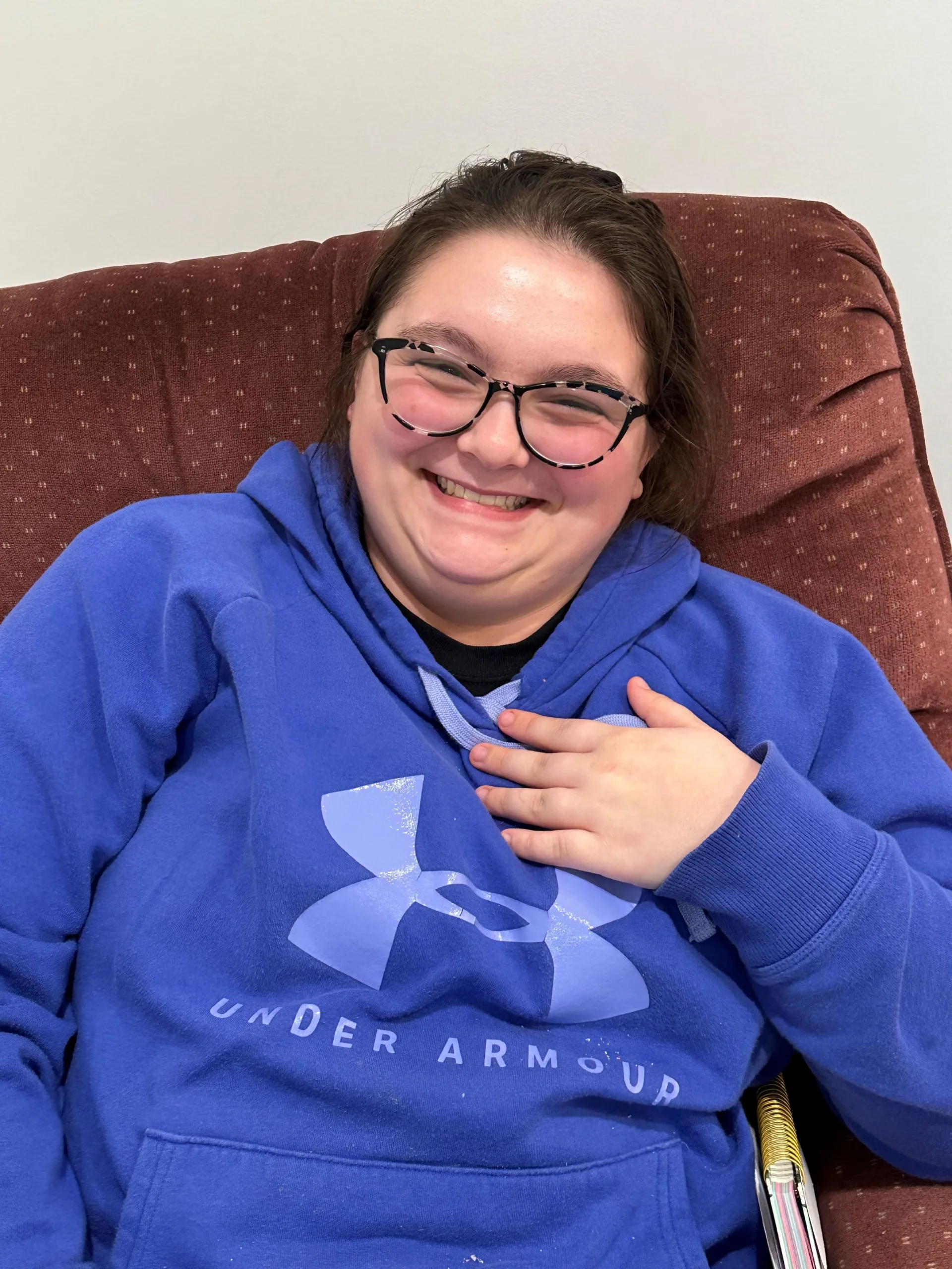 Kami smiling while wearing a blue Under Armour hoodie, celebrating her achievements at AmeriServe.